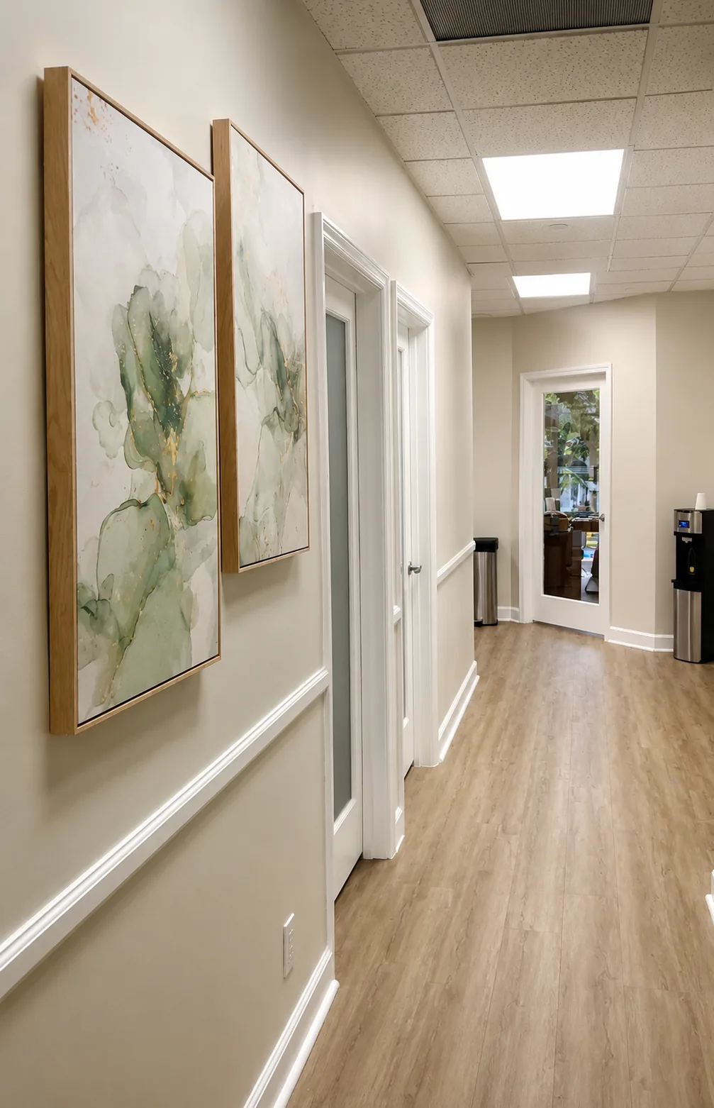 Interior hallway with wood-look flooring, framed green abstract artwork and white doors