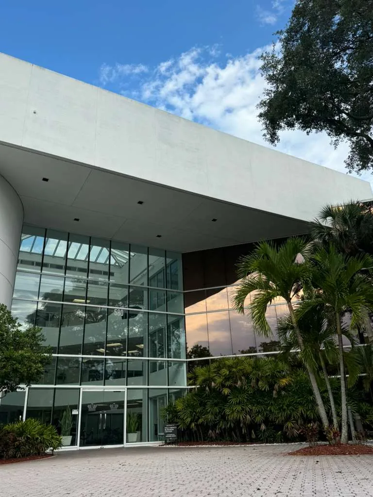 Glass front entrance of the office building at 580 Village Blvd, West Palm Beach, with palm trees beside the doors